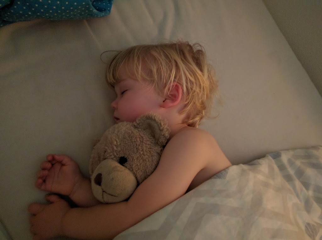 Boy sleeping with his teddy in bed