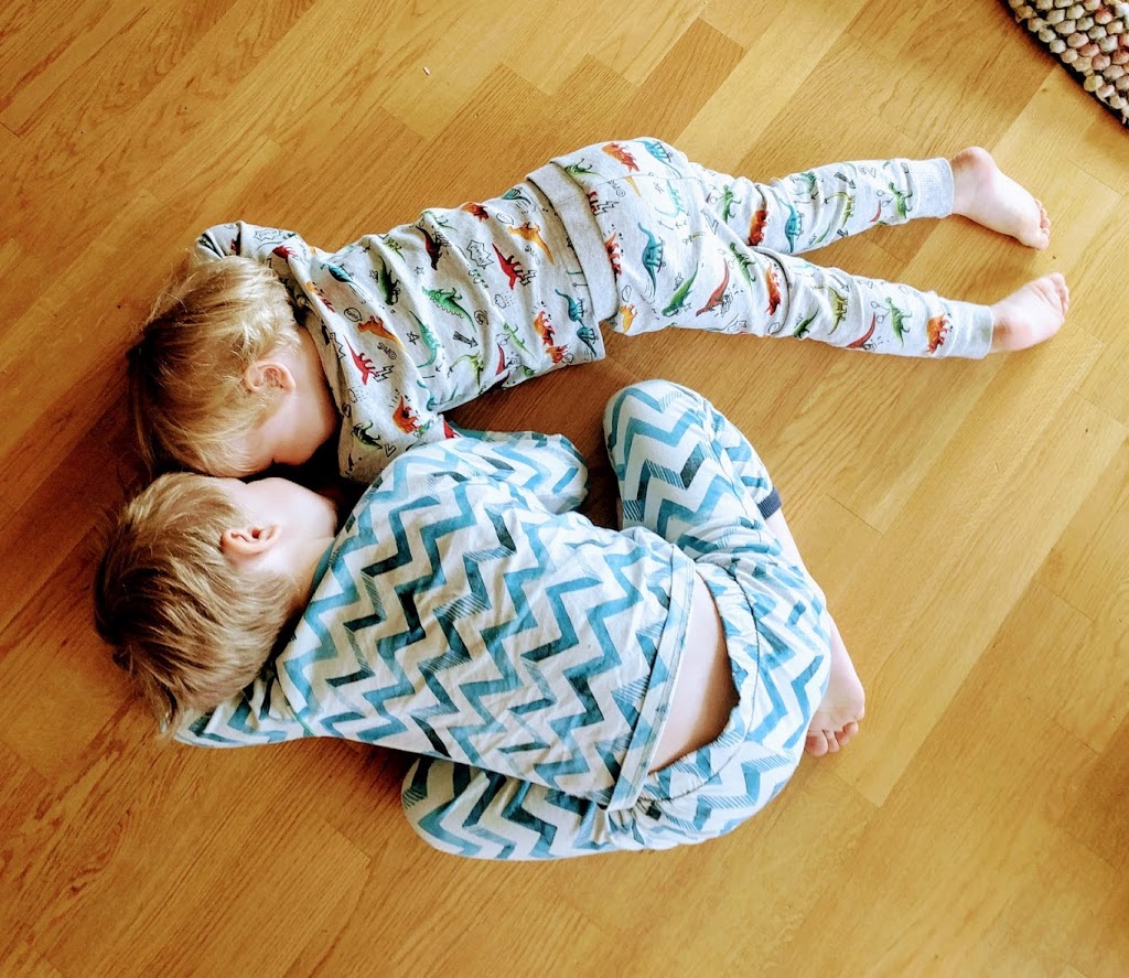 Two boys in pyjamas lying on the floor and talking